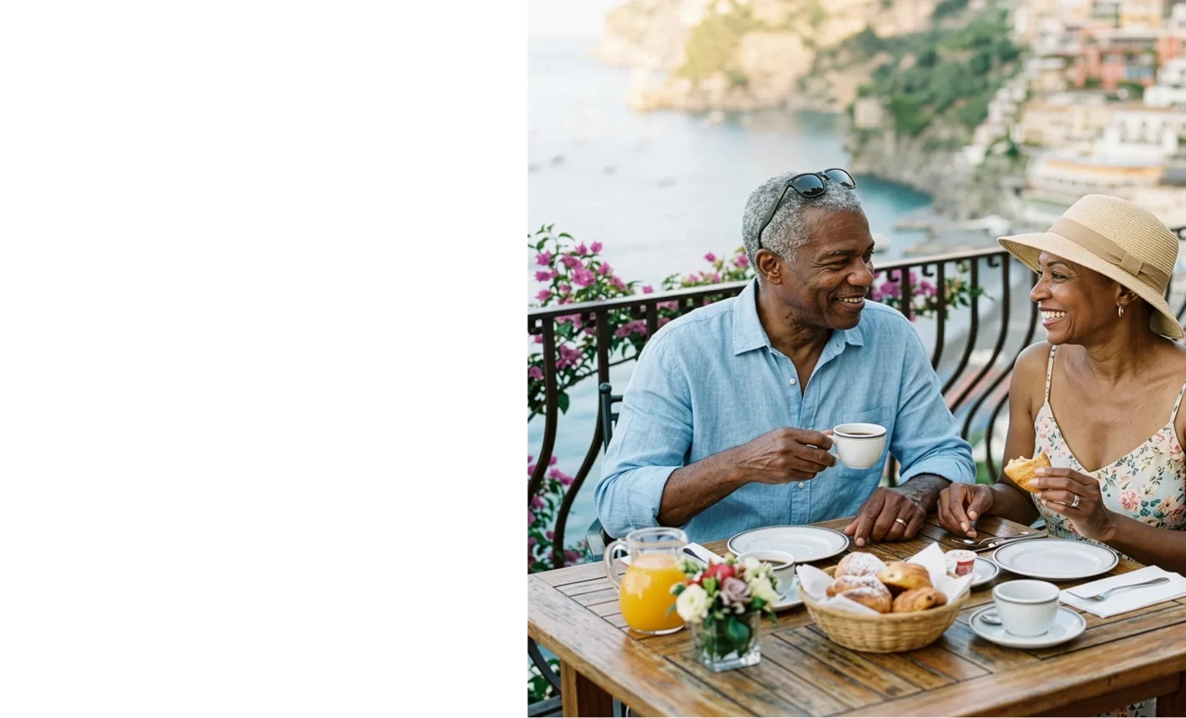 Happy retired couple enjoying breakfast together on a sunny Amalfi Coast terrace overlooking the sea.